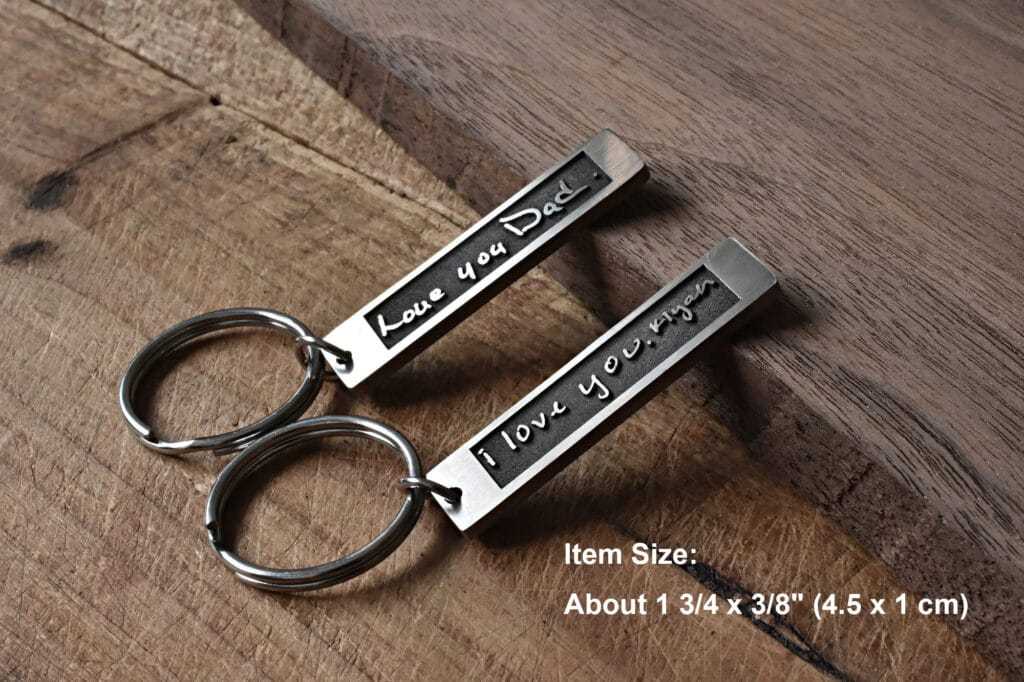 Personalized metal keychains with Love you Dad and I love you engravings on wooden surface.