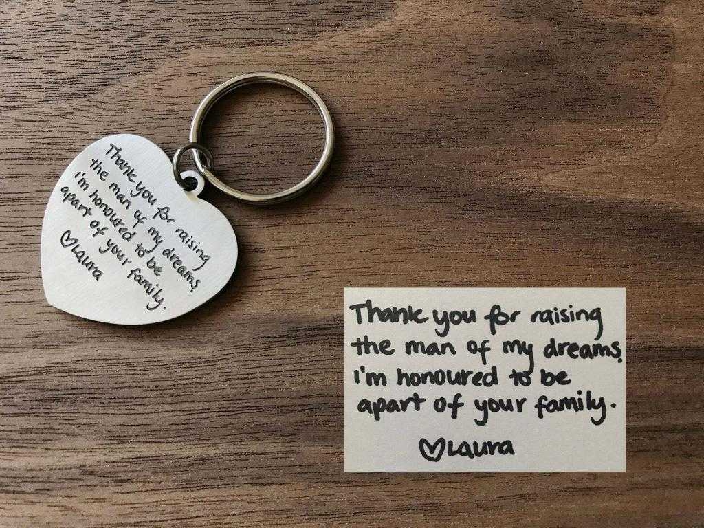 Heart-shaped keychain with heartfelt thank you message from Laura to a family, alongside a handwritten note on wood.