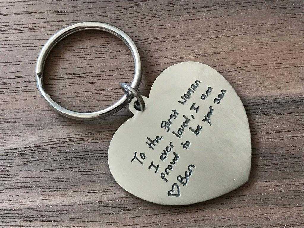 Heart-shaped keychain with engraved message from son to mother on a wooden surface. Perfect sentimental gift.
