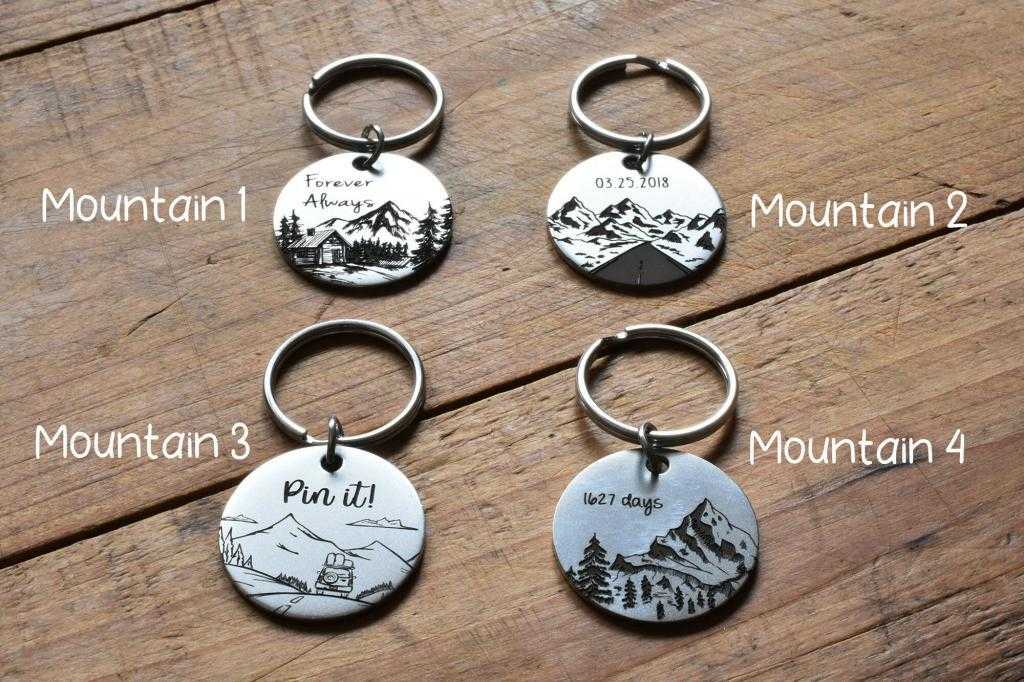Four engraved mountain-themed keychains on wood surface, labeled Mountain 1 to Mountain 4.