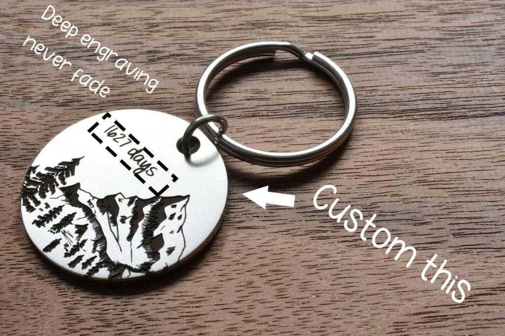 Customizable engraved keychain with mountain design on wooden background. Perfect for personalized gifts.