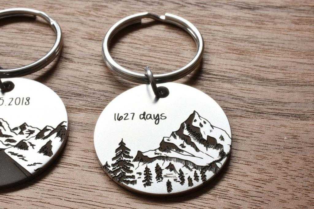 Engraved mountain keychain on wood surface, marked 1627 days, showcasing custom design and craftsmanship.