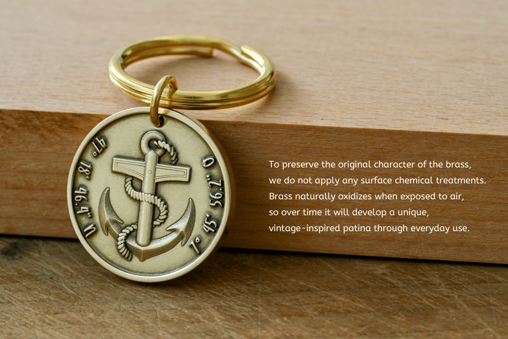 Brass keychain medallion with an anchor and engraved coordinates, next to text explaining that untreated brass naturally oxidizes to form a unique vintage patina over time