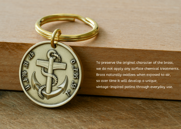 Brass keychain medallion with an anchor and engraved coordinates, next to text explaining that untreated brass naturally oxidizes to form a unique vintage patina over time