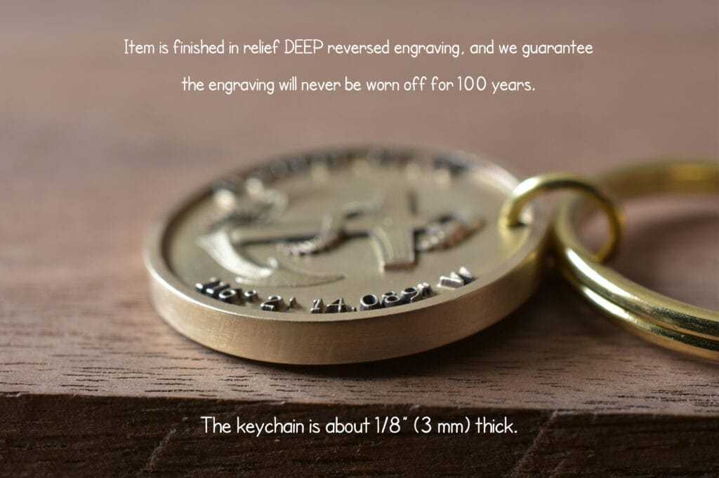 Close-up of a gold keychain with deep engraved design, guaranteed for 100 years, 1/8 inch thick on wooden surface.