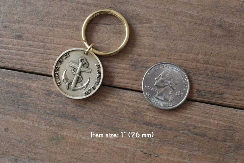 Nautical keychain with anchor design beside US quarter for size comparison on wooden surface.