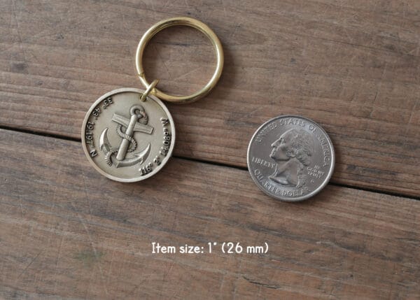 Nautical keychain with anchor design beside US quarter for size comparison on wooden surface.
