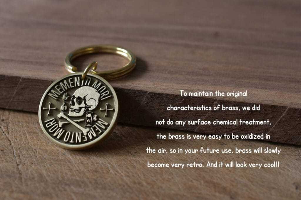 Brass keychain with Memento Mori design on wood background, emphasizing natural aging patina for retro aesthetic.
