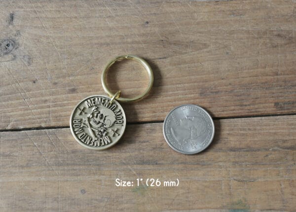 Memento Mori skull keychain next to a quarter on wooden surface, 1-inch diameter (26mm).