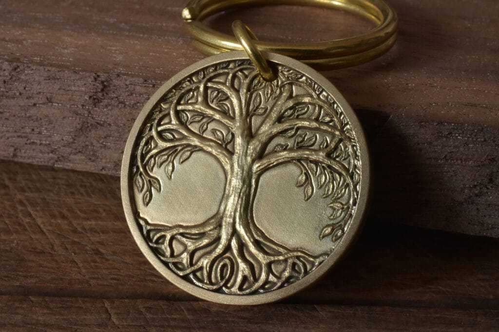 Golden Tree of Life pendant keyring on wooden background, symbolizing growth and strength.