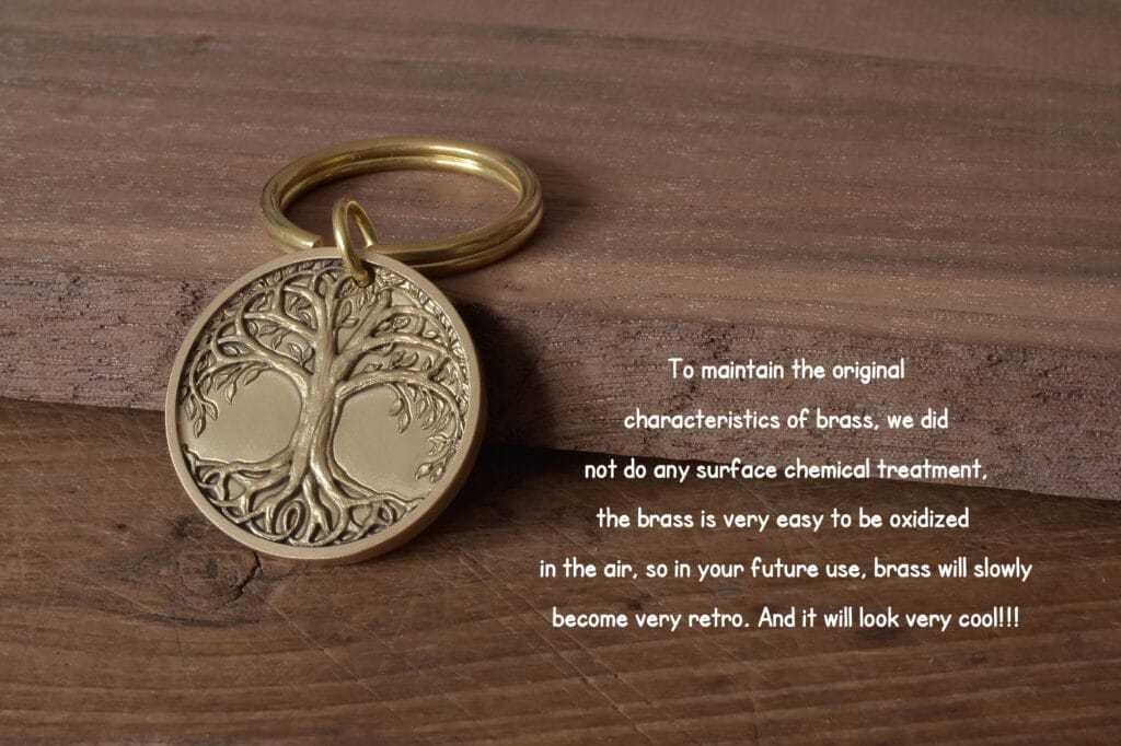 Brass keychain with an engraved tree design, untreated surface for natural oxidation, on wooden background.