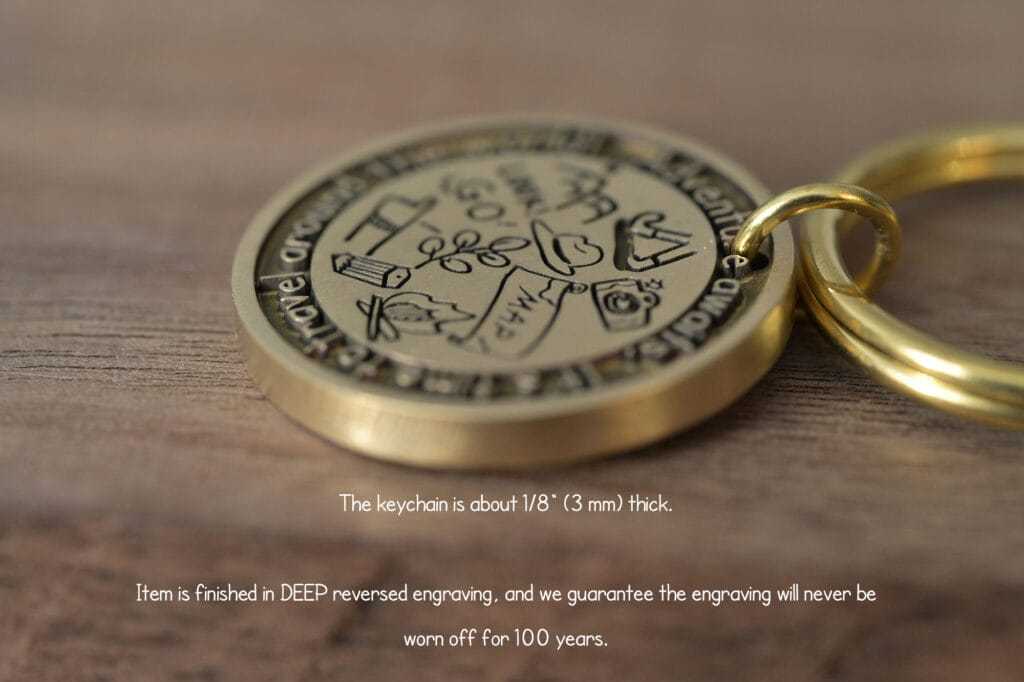 Close-up of a gold keychain with deep engraving, showcasing travel-themed icons on a wooden surface.