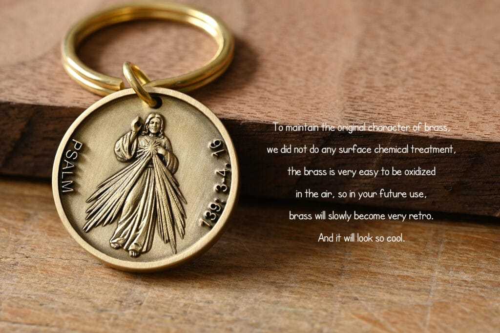 Brass keychain with religious engraving on a wooden surface, highlighting its natural oxidation process for a vintage look.
