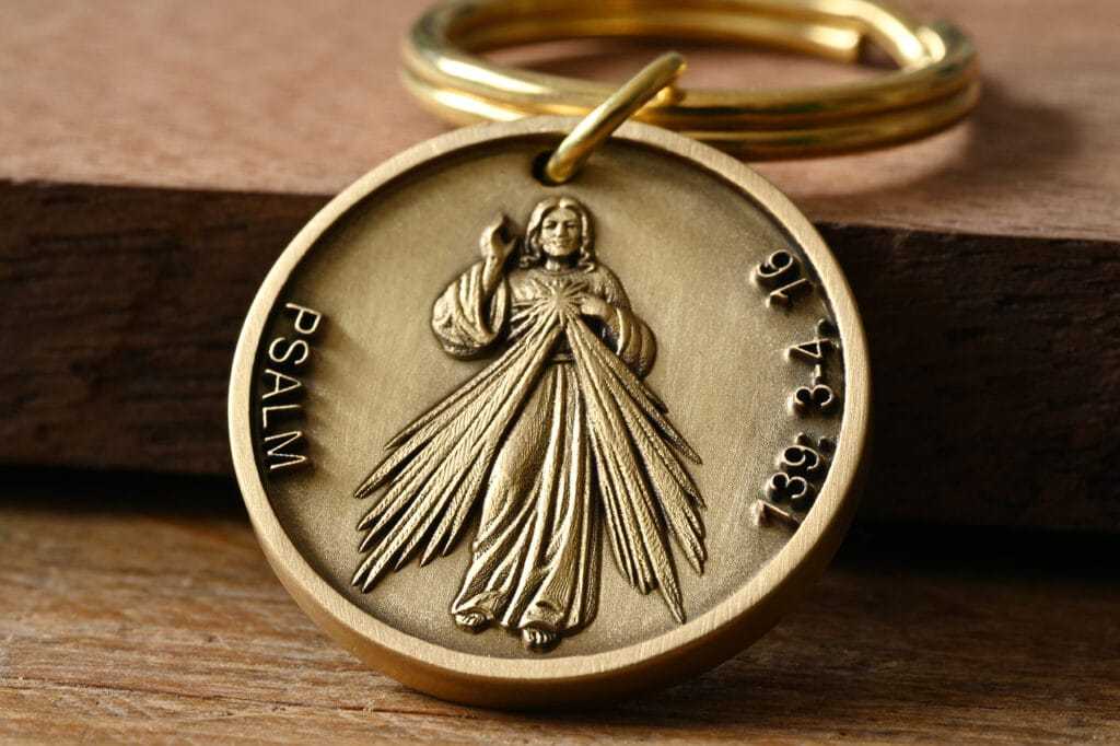 Bronze religious medallion featuring a figure with rays, Psalm text, and keyring on wood surface.