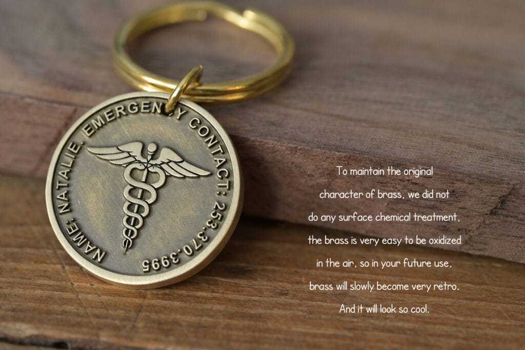 Brass emergency contact keychain with Caduceus symbol, highlighting natural oxidation and vintage appeal.
