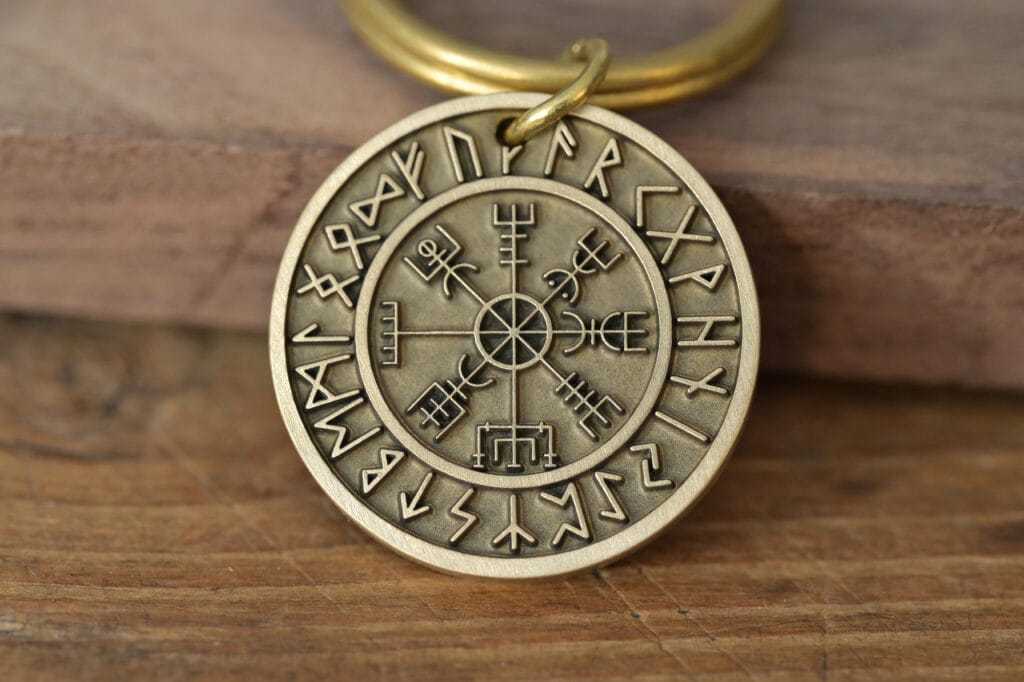 Close-up of a brass Viking runic pendant with ancient symbols on a wooden surface.