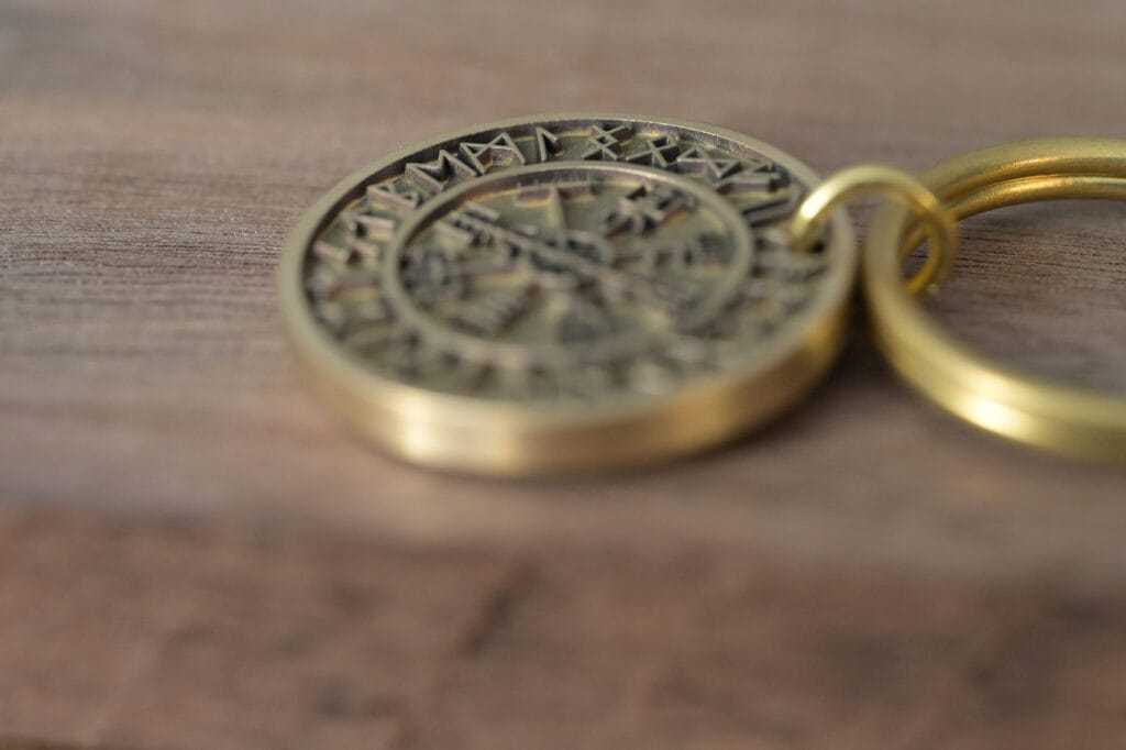 Close-up of an ancient brass coin keychain with intricate engravings on a wooden surface.