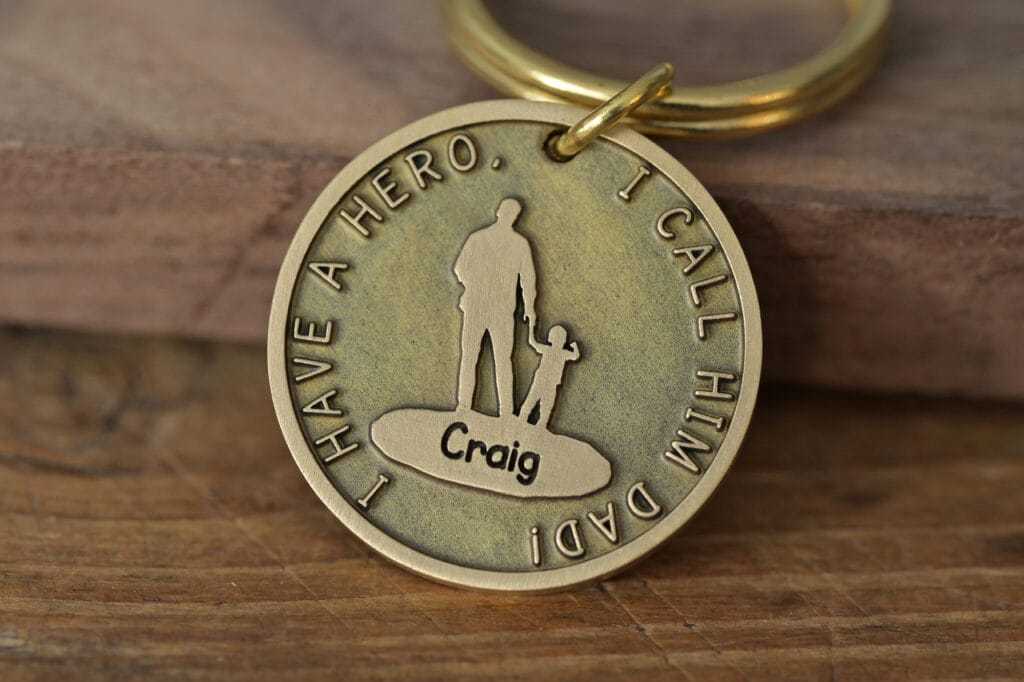 Bronze keychain engraved with I Have a Hero, I Call Him Dad, featuring a silhouette of a father and child.