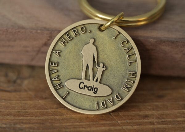 Bronze keychain engraved with I Have a Hero, I Call Him Dad, featuring a silhouette of a father and child.