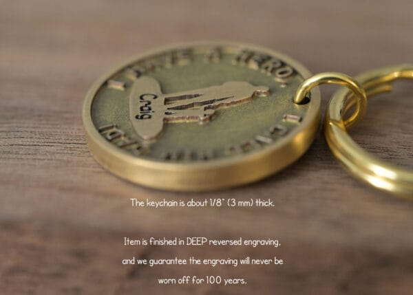 Close-up of a bronze keychain with deep reversed engraving, promised to last 100 years, on a wooden surface.