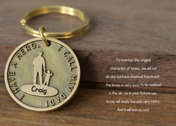 Brass keychain with I Have a Hero, I Call Him Dad engraved, features father and child silhouette.