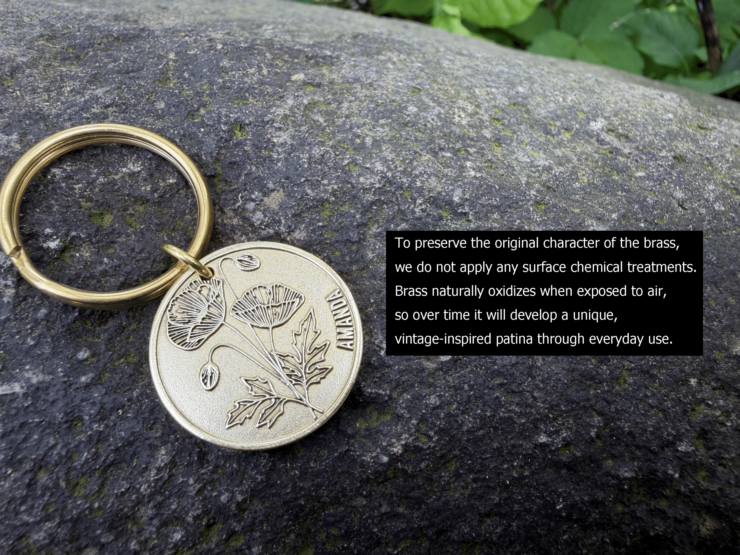 Brass keychain with poppy engraving and Ahanda, on rock background. Patina develops naturally in everyday use.