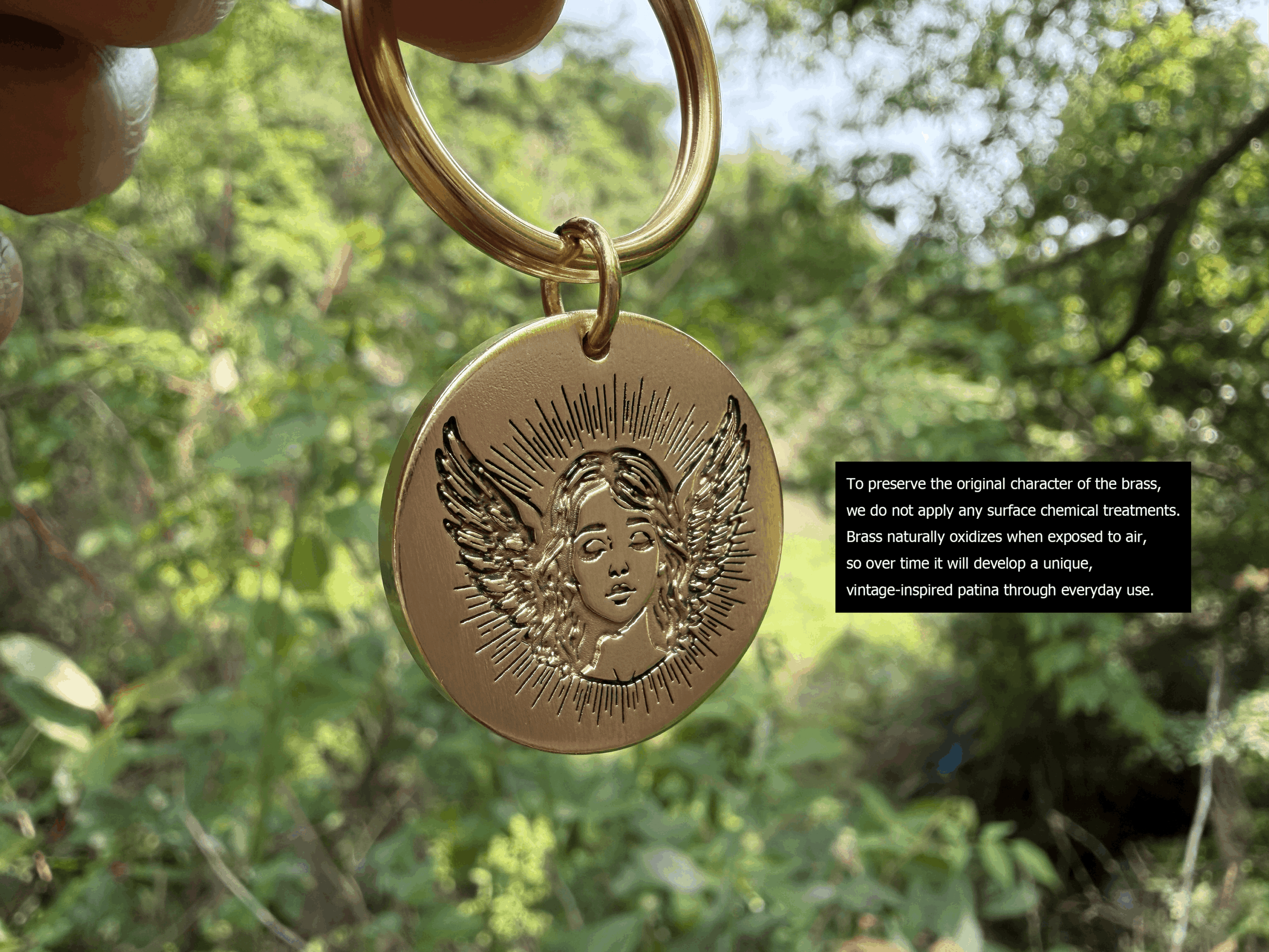 Brass keychain with angel engraving, hanging outdoors, highlighting natural, untreated patina development over time.