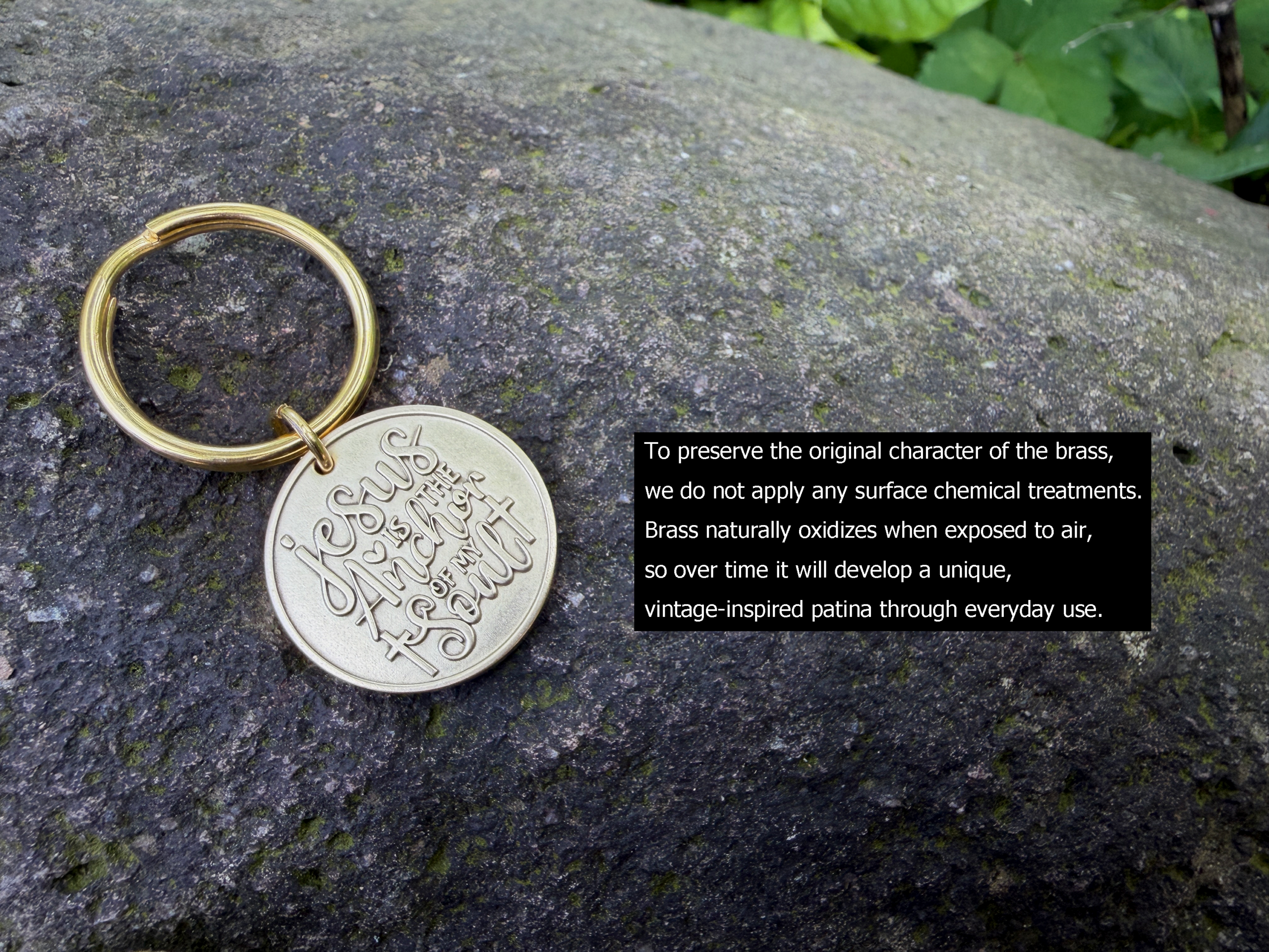 Brass keychain on rock engraved with Jesus is the anchor of my soul, emphasizing its natural oxidized patina development.