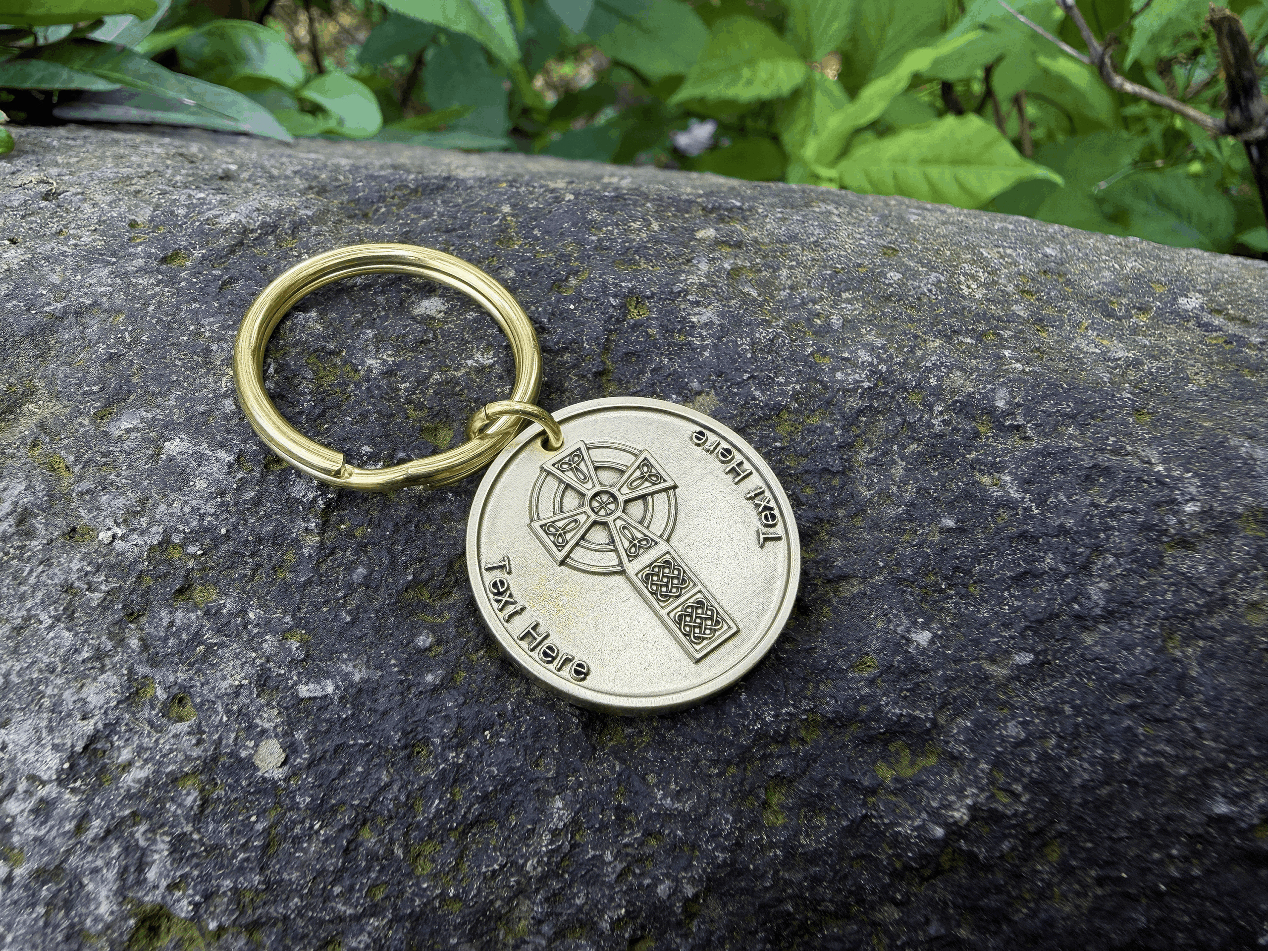 Gold keychain with Celtic cross design on stone surface outdoors. Text space available for personalization.