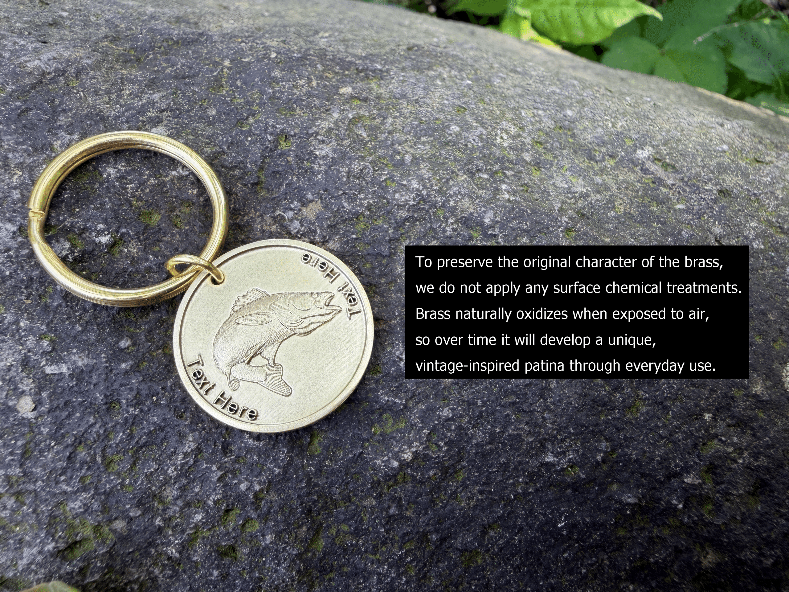 Keychain with engraved fish on brass, laying on rock. Text about brass oxidation and vintage-inspired patina development.