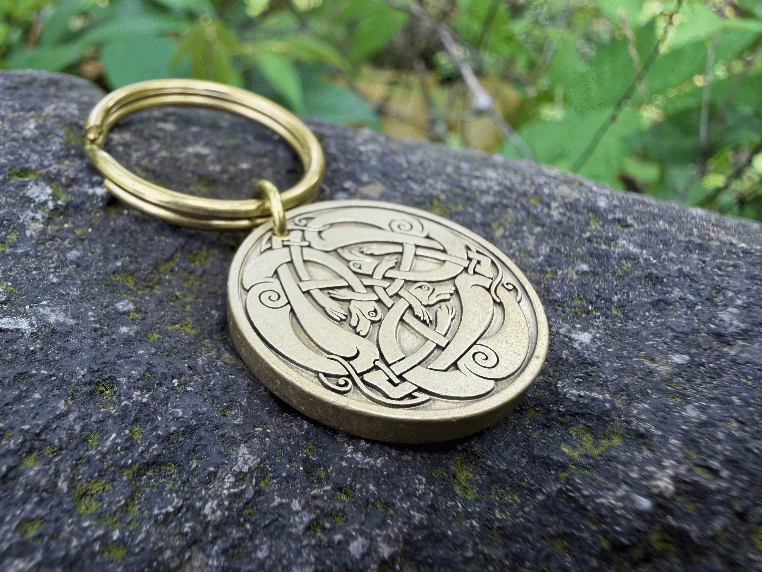 Celtic knot engraved keychain on stone with intricate loops and swirls design, gold finish, natural background.