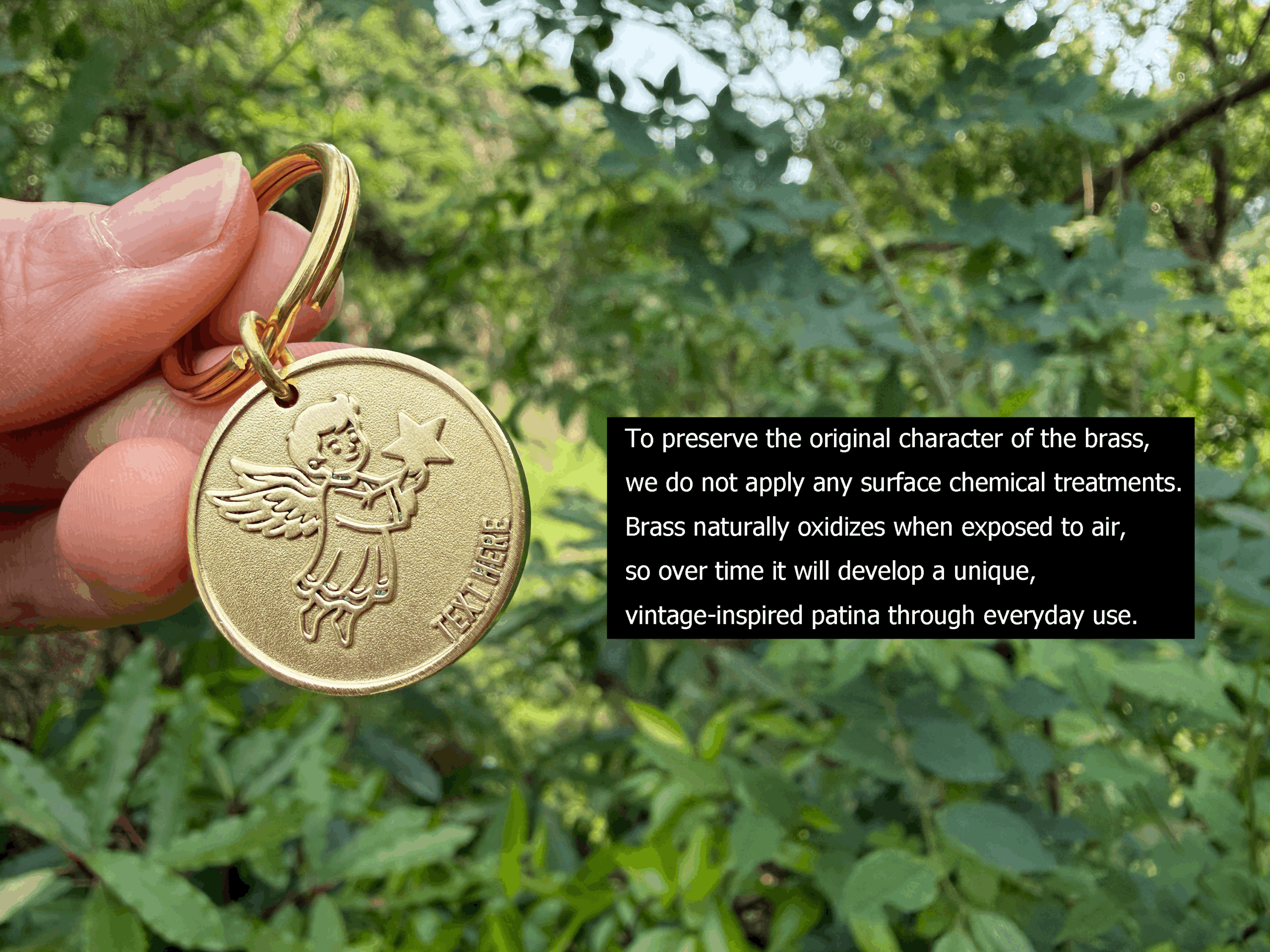 Hand holding a brass keychain with an angel engravement in a lush green garden, highlighting natural oxidation benefits.