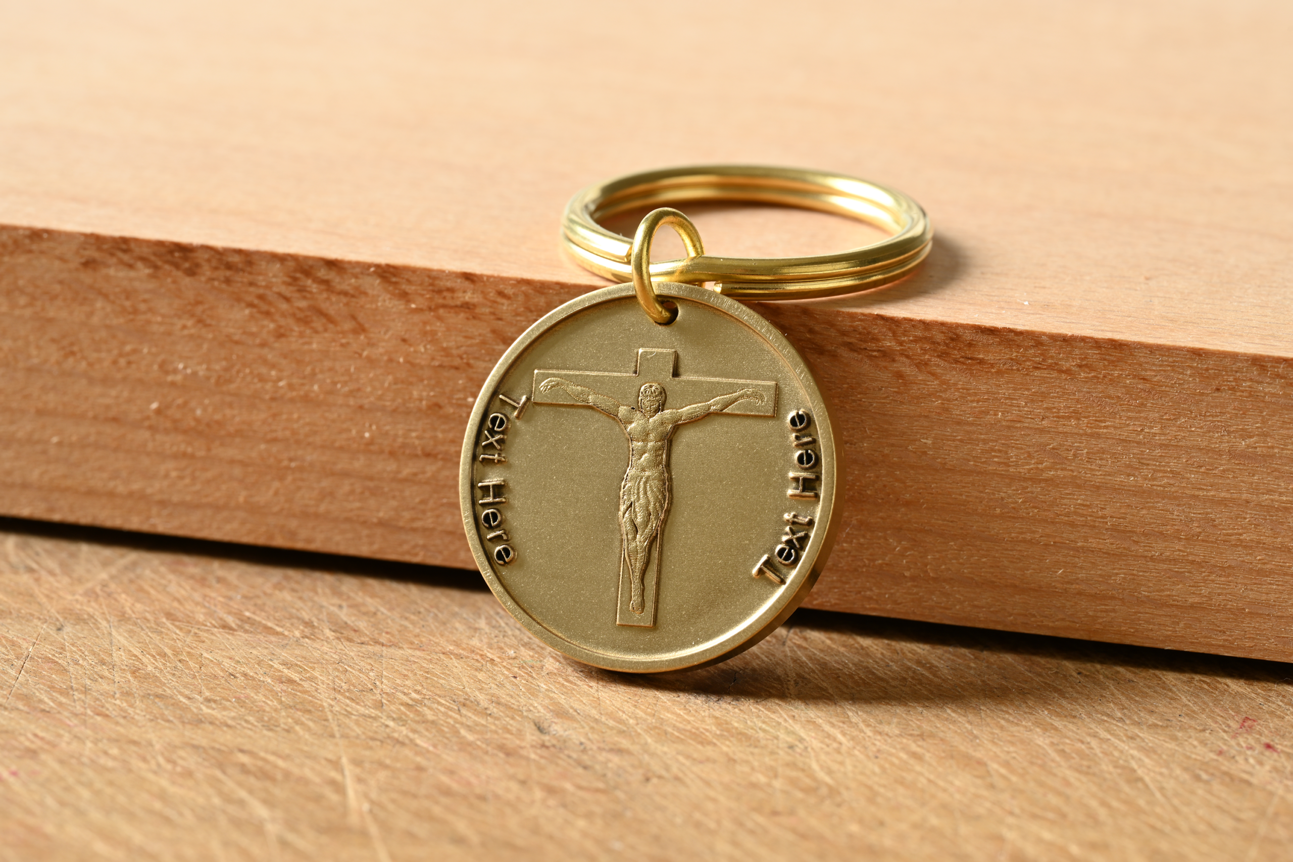 Gold circular keychain with an embossed crucifix and placeholder text on either side