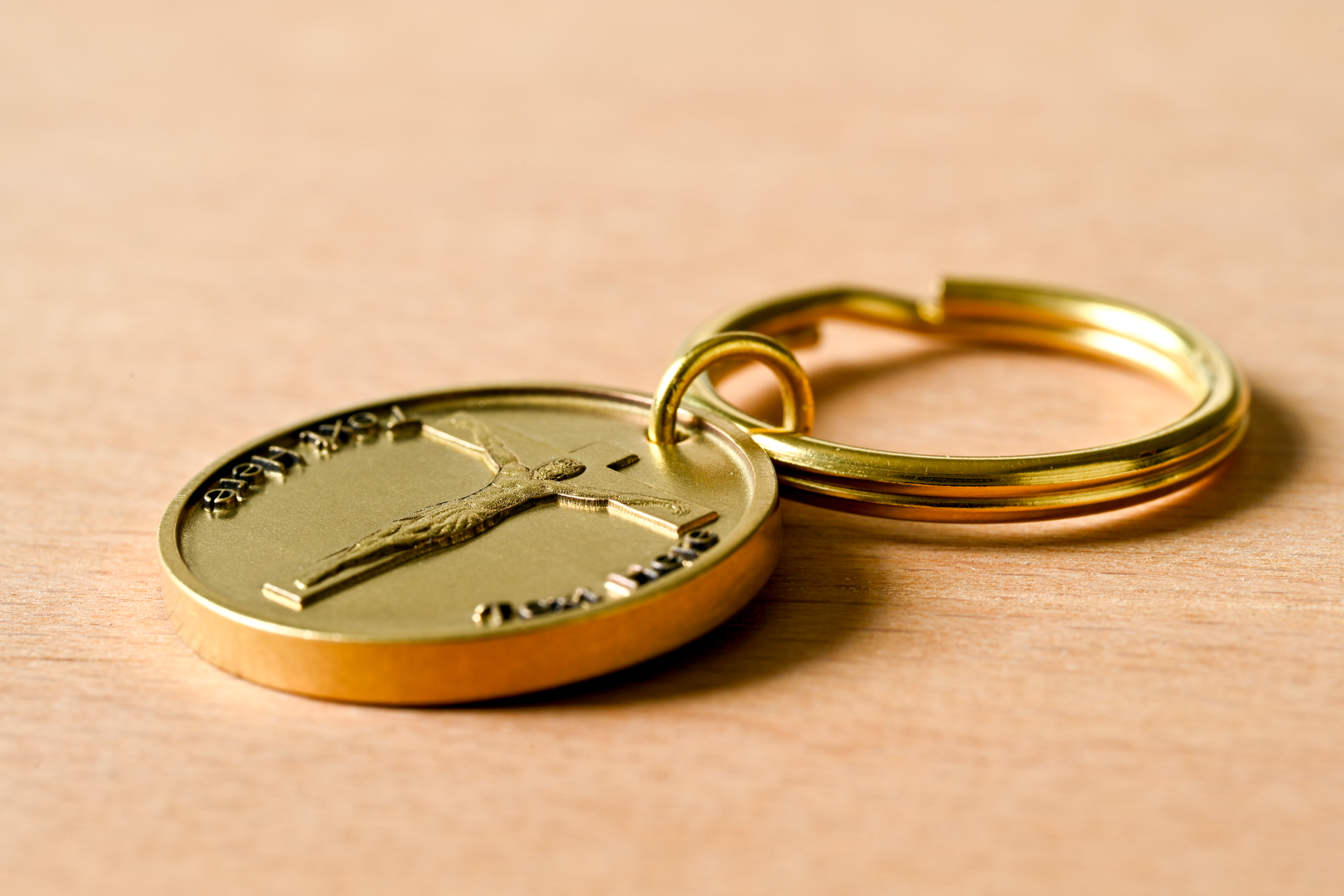 Gold-colored keychain with a circular medallion featuring a crucifix
