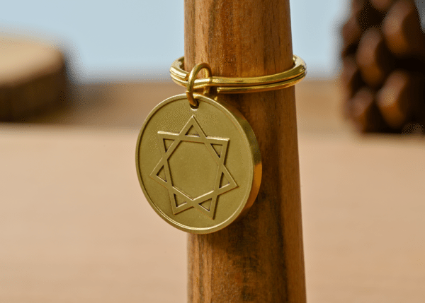 Round gold keychain featuring an engraved seven-pointed star