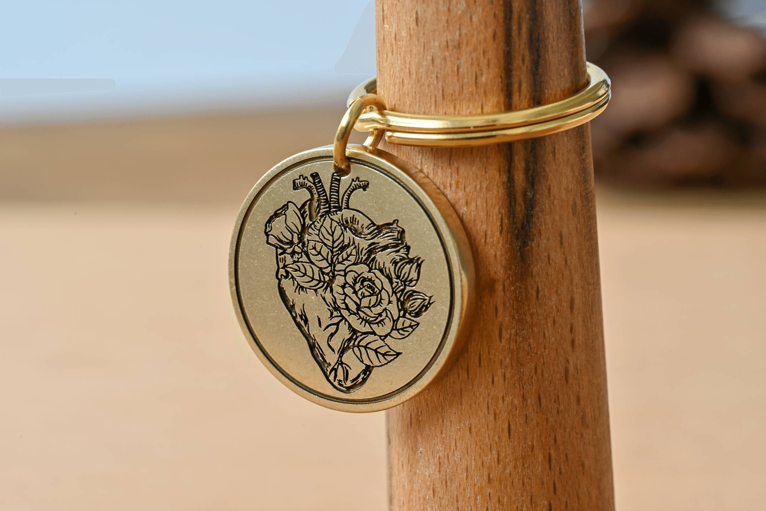 Round gold keychain medallion engraved with an anatomical heart and blooming roses