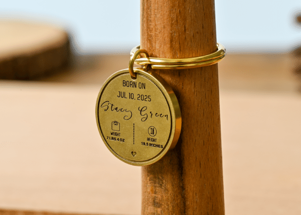 Engraved brass keychain tag displaying Stacy Green, born Jul 10, 2025, weight 7 lbs 4 oz, height 19.5 inches