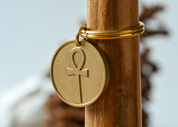 Gold circular keychain featuring an embossed Egyptian ankh symbol
