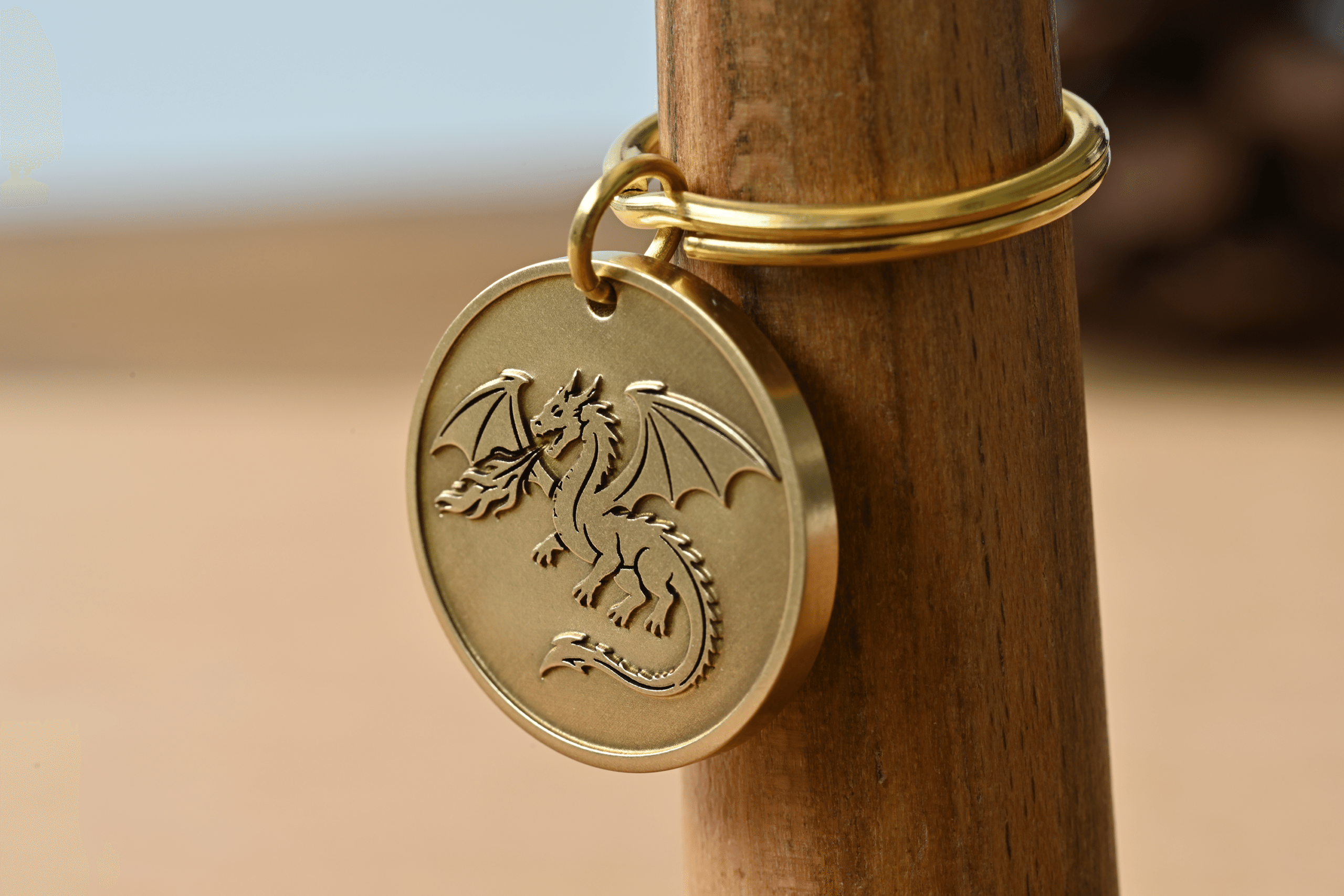 Brass circular keychain tag engraved with a fire-breathing dragon