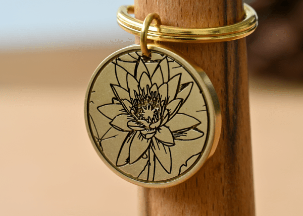 Round gold brass keychain featuring a detailed engraved lotus flower