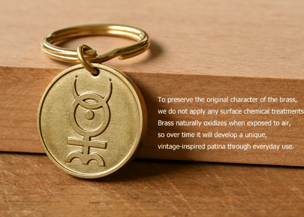 Brass keychain with an engraved symbol next to text explaining that untreated brass naturally oxidizes to develop a unique patina over time