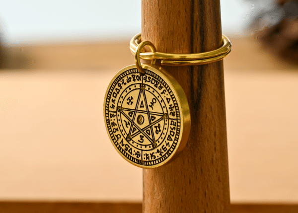 Brass keychain medallion engraved with a pentagram and mystical symbols