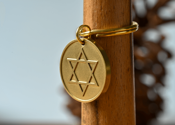 Gold circular medallion featuring an engraved Star of David hanging on a wooden post