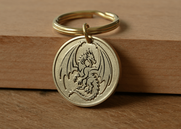 Round brass key ring tag engraved with a dragon with wings spread