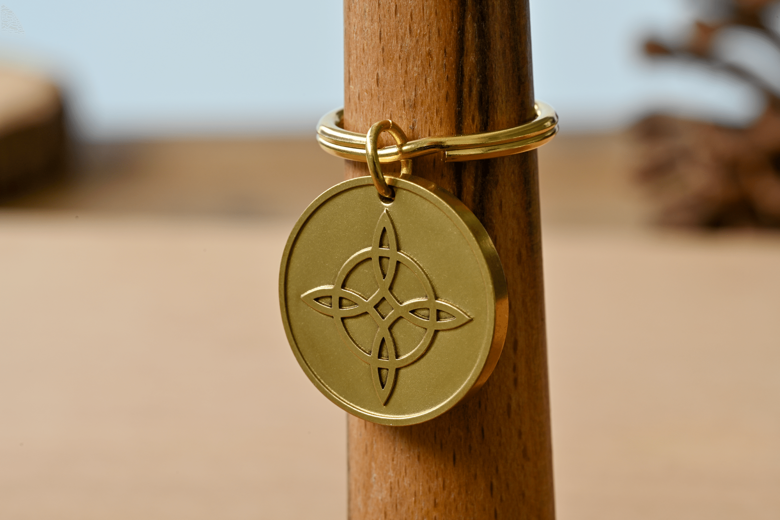 Gold circular keychain tag featuring an engraved witch's knot design