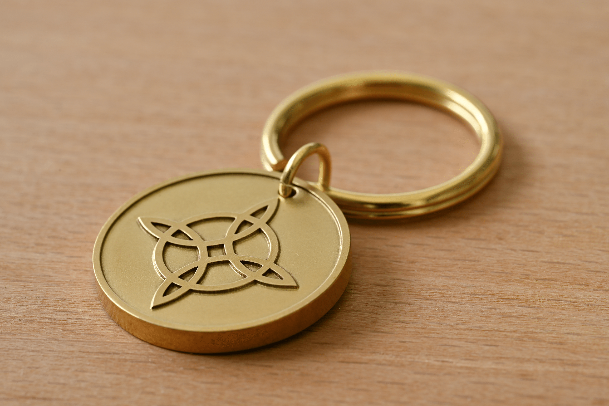 Brass keychain with a circular pendant featuring a Celtic knot on a wooden surface