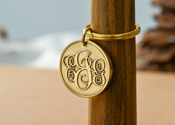 Round gold brass keychain pendant with an ornate cursive monogram design