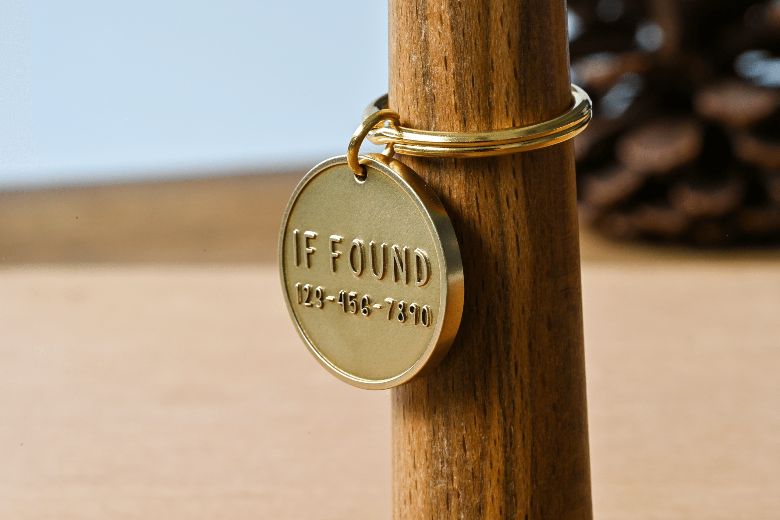 Round brass tag on a key ring engraved with IF FOUND 123-456-7890