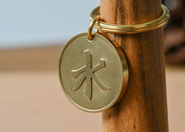 Round brass key ring medallion engraved with the Chinese character for wood