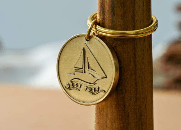 Round brass keychain engraved with a sailboat and the words BEST TRIP